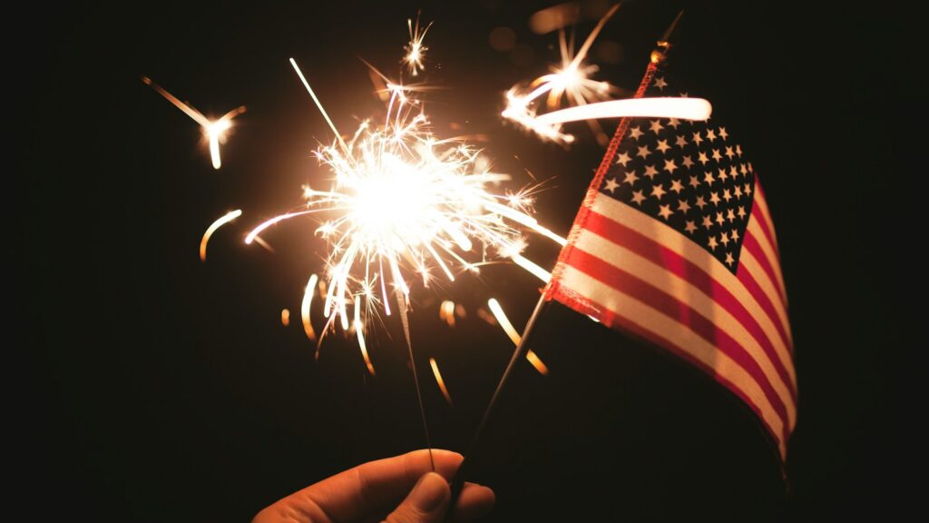 time lapse photography of sparkler and U.S.A flag let